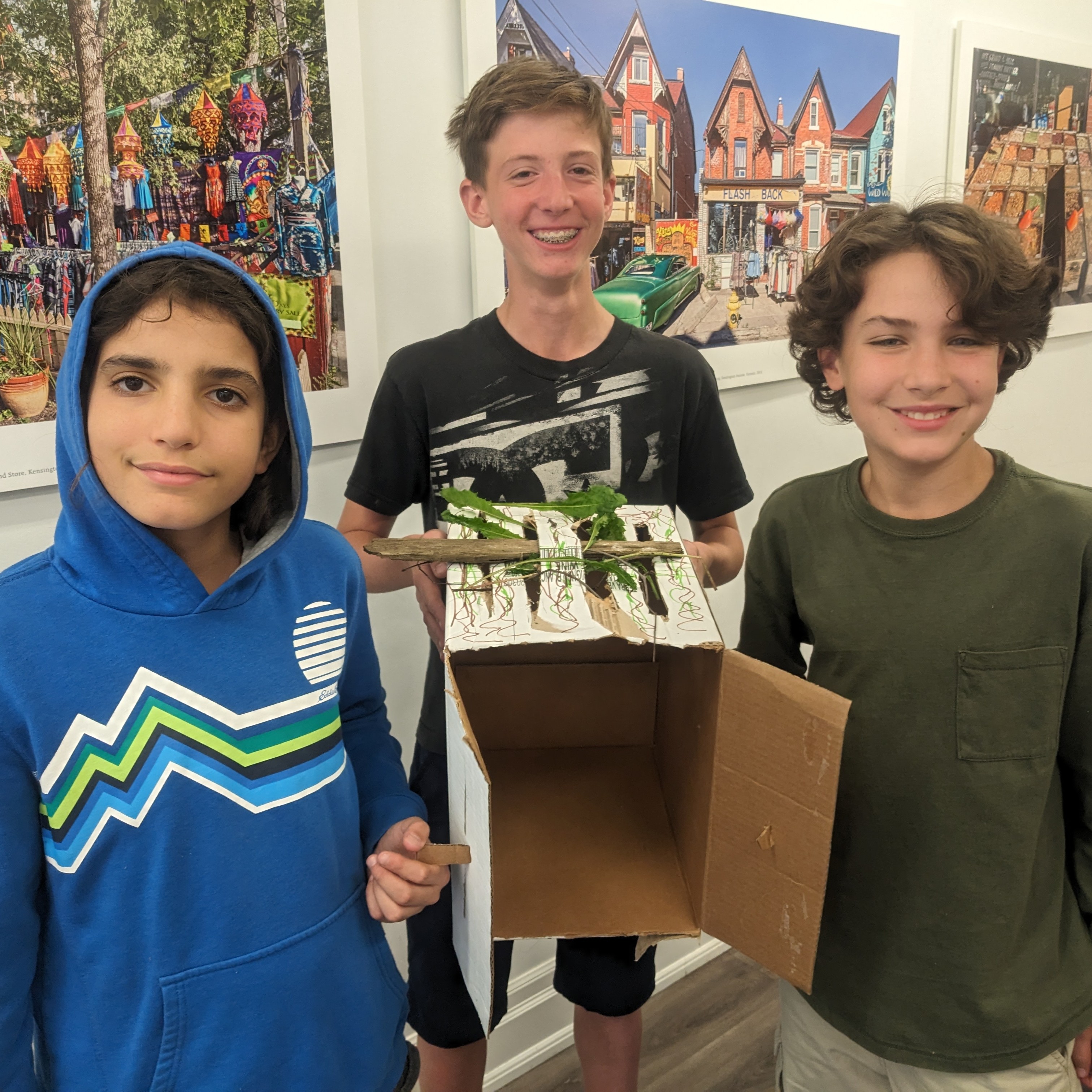 ATID students smiling and holding up their model sukkah